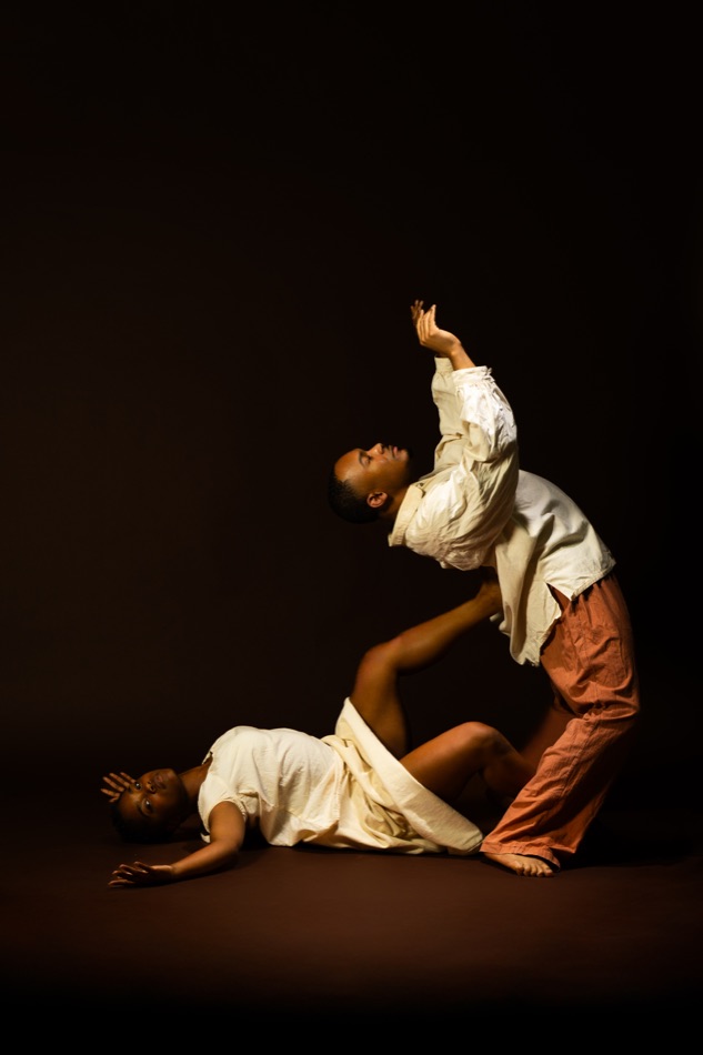 A performer lifting another toward the light