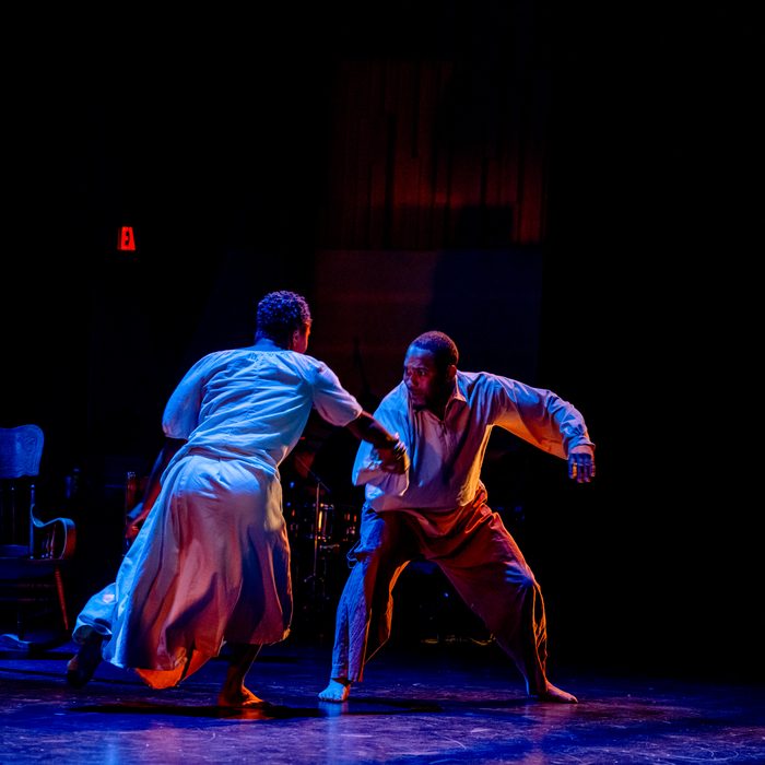 Two men locked together mid-struggle in blue light